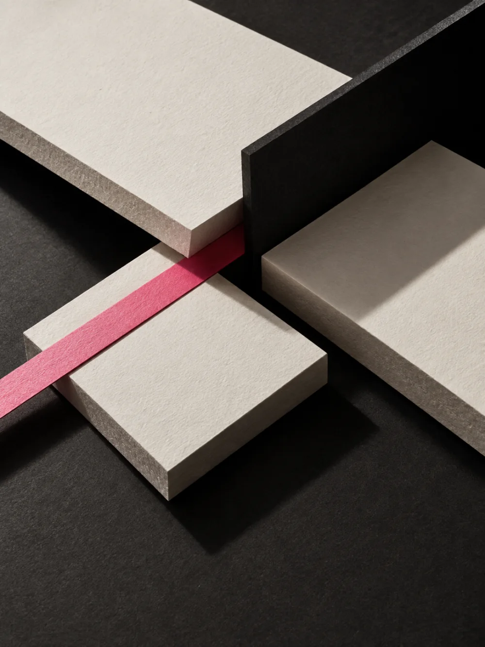 Blocks of paper and black board crossing, with a pink band between them